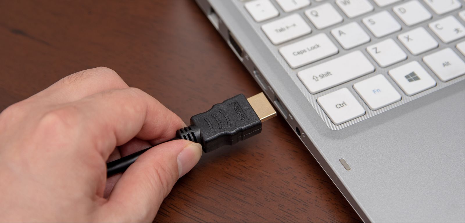person connects the HDMI plug to the laptop