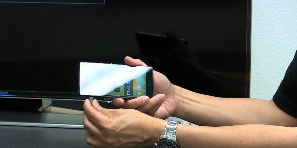 man connects the USB cable to the smartphone on the background of the LCD TV