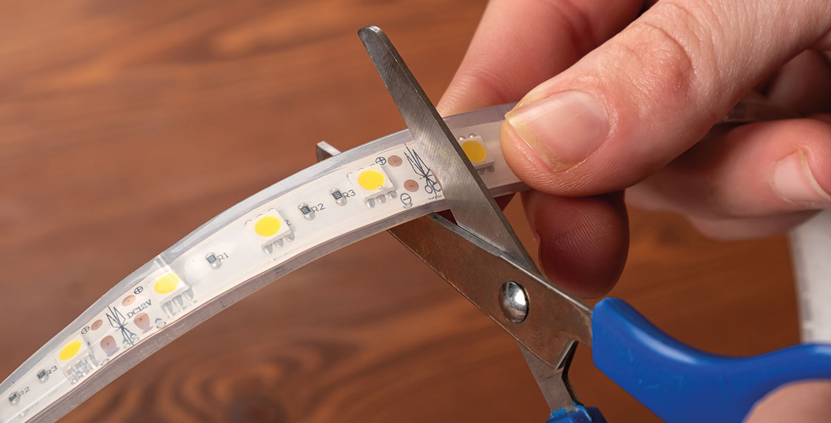 hand cutting the LED strip with scissors at the intended spot
